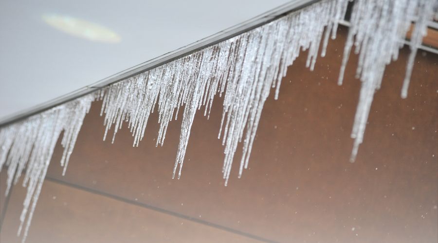 gutter ice and icicles due to poor venting and a gutter that is clogged with snow